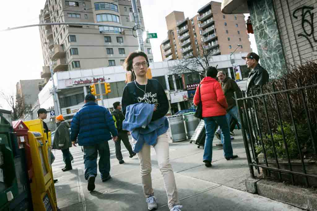 Woman with headphones walking in Flushing Queens street photography series