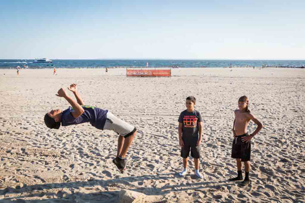 Coney Island street photography of a kid doing a back flip