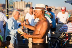 Coney Island street photography of a shirtless man playing maracas