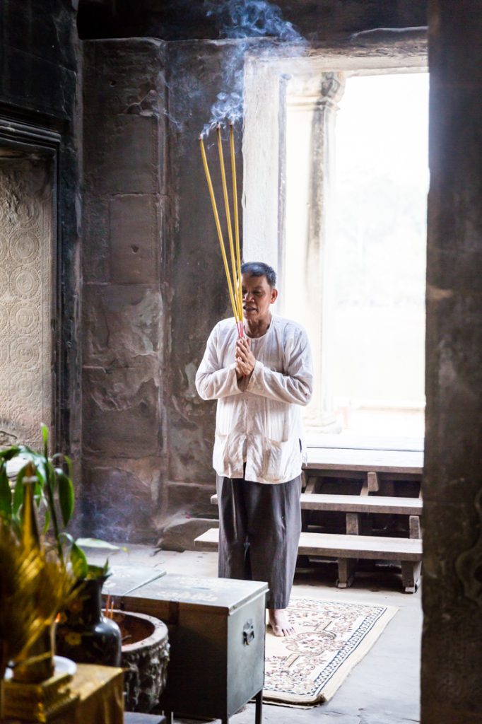 Man with long incense sticks for an Angkor Wat temple guide