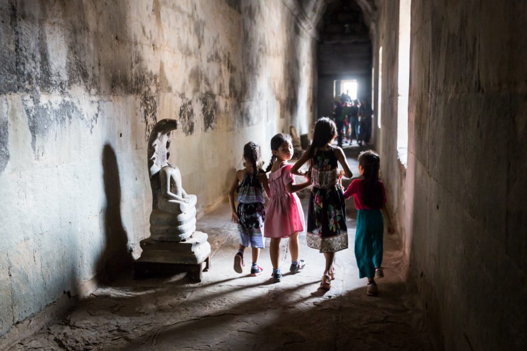 Girls walking down a hallway at Angkor Wat for an article on Angkor Wat travel tips