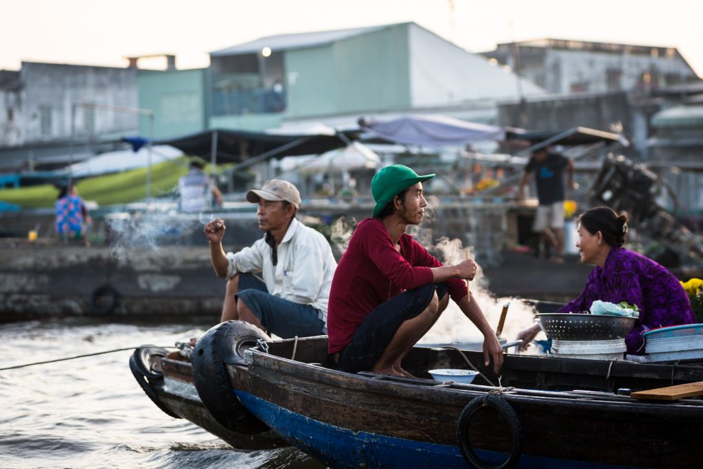 Men sitting on boats at the Cai Rang Floating Markets