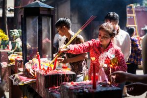 Woman lighting incense at the Ba Thien Hau temple for article on Ho Chi Minh City street photos