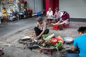 Man preparing fish in the street for article on Ho Chi Minh City street photos