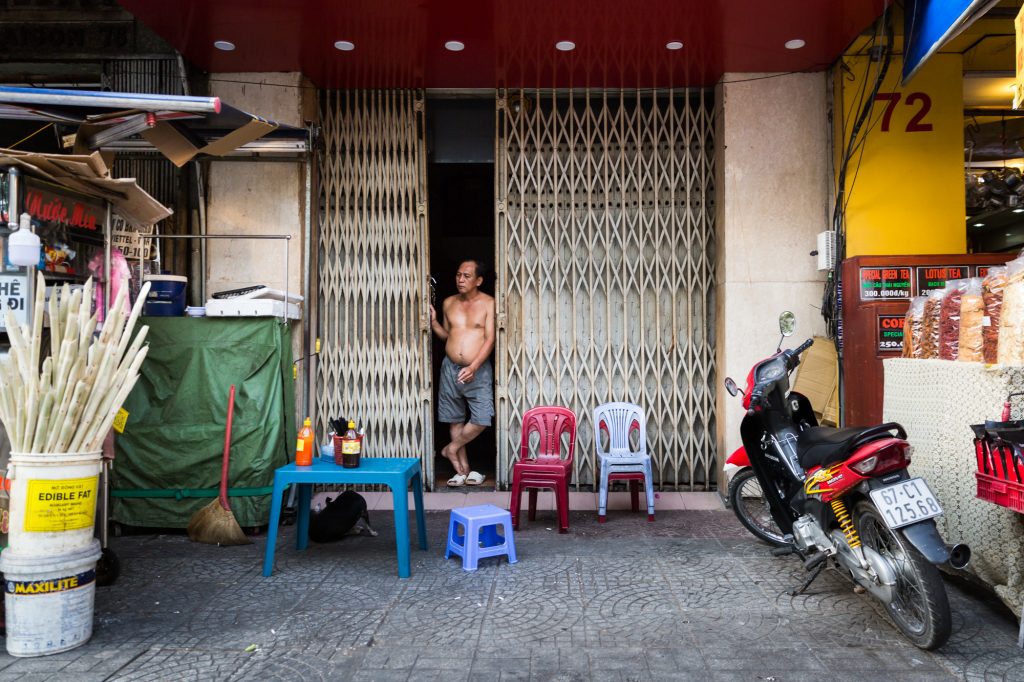 Shirtless man in doorway for article on Ho Chi Minh City street photos