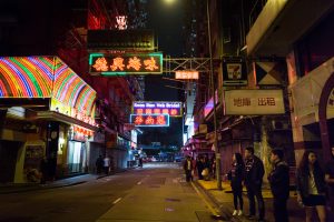 People looking at neon signs for a Hong Kong travel guide article