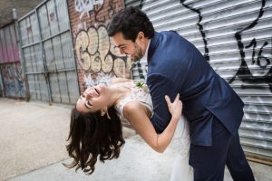 Bride and groom dancing against graffiti wall