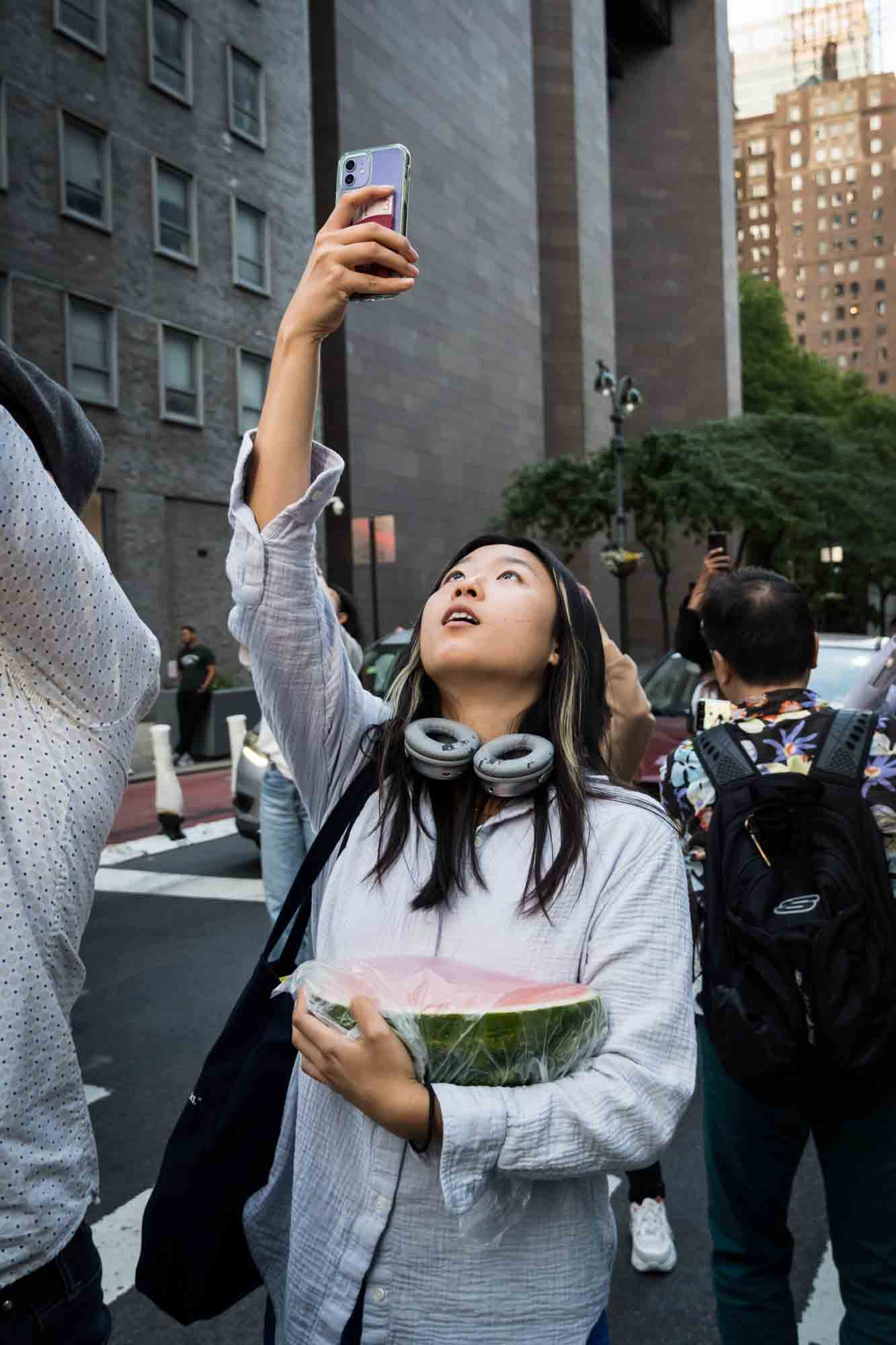 Asian woman in a NYC street with cellphones in hand during Manhattanhenge