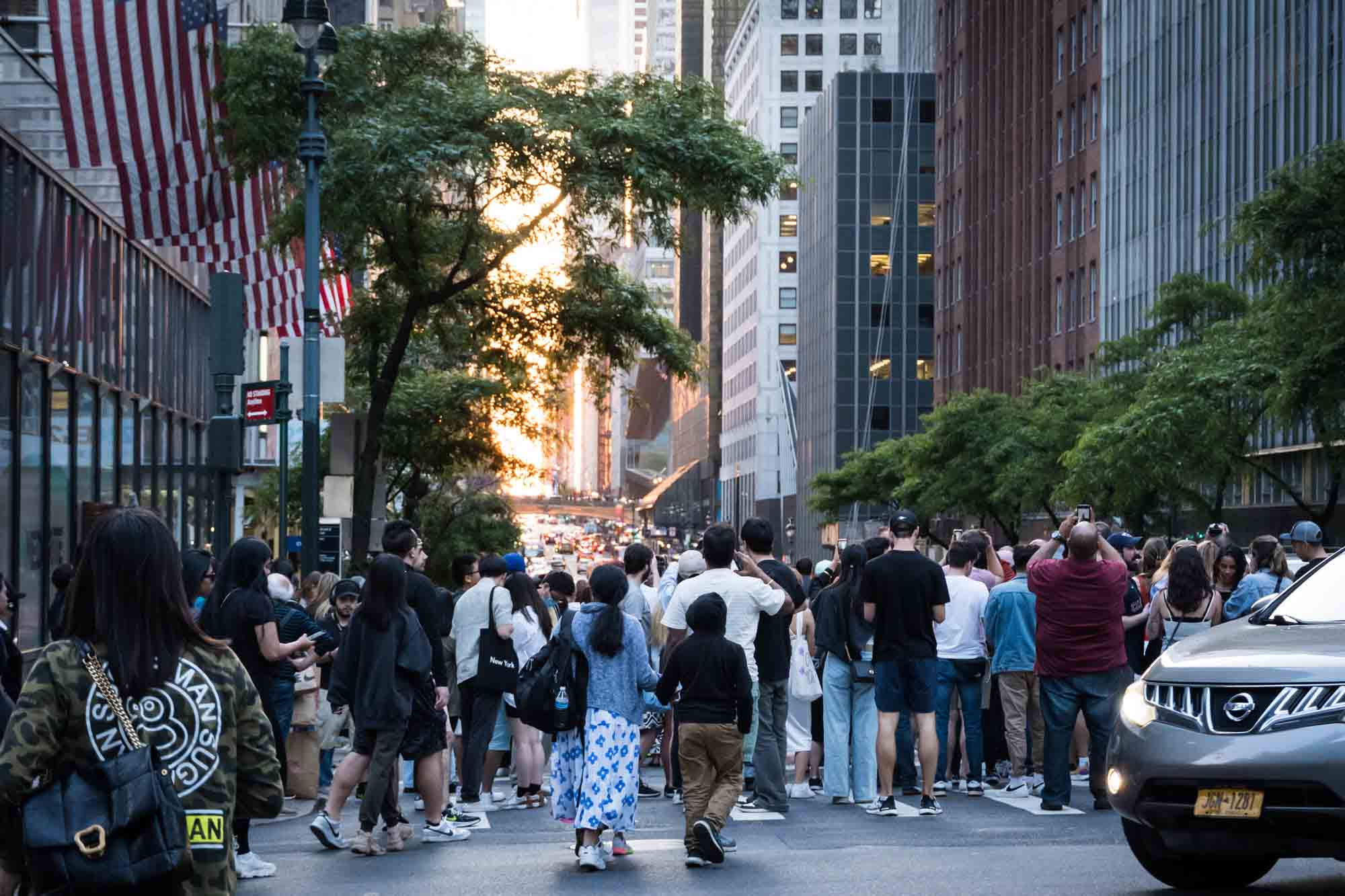 Tourists in a NYC street with cellphones in hand during Manhattanhenge