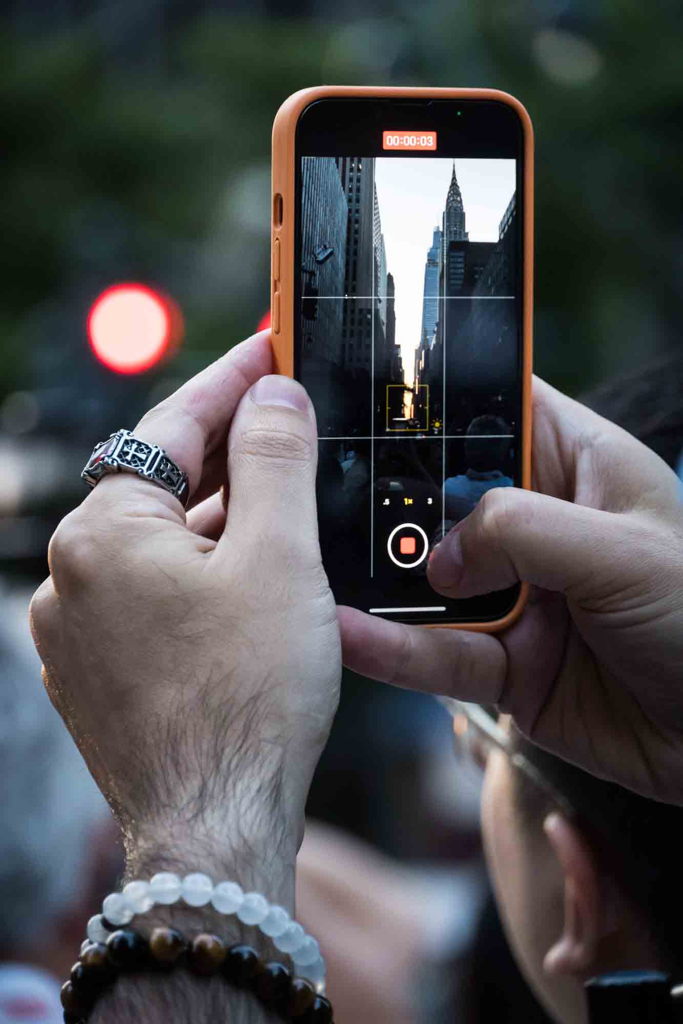 Hands holding cellphone capturing Manhattanhenge
