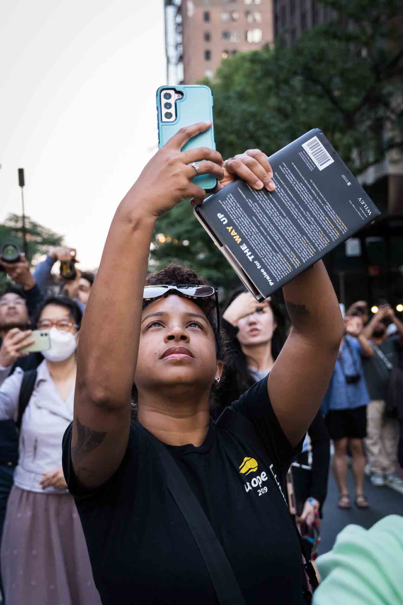 African American woman in a NYC street with cellphones in hand during Manhattanhenge