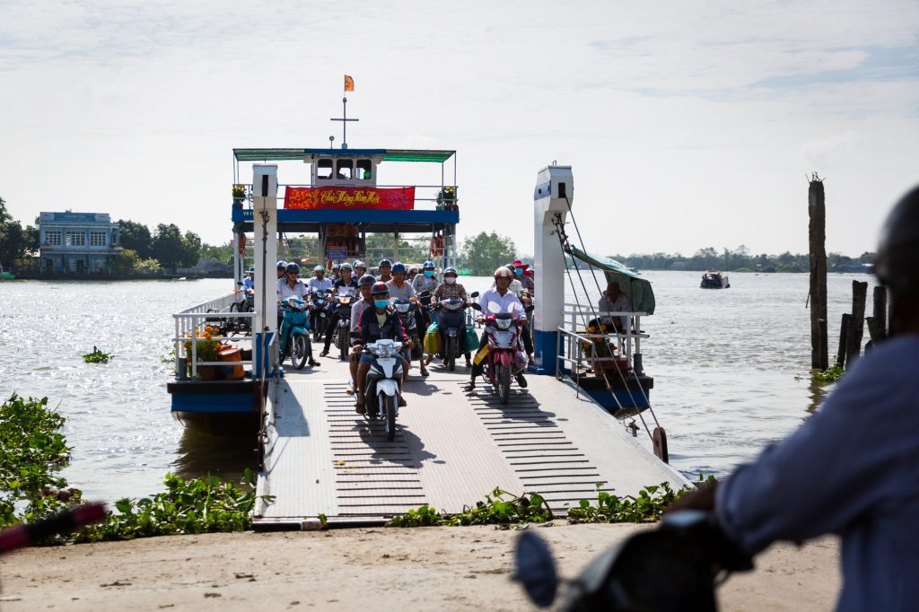 Motorcycles coming off a ferry for an article on the Cai Be Floating Markets