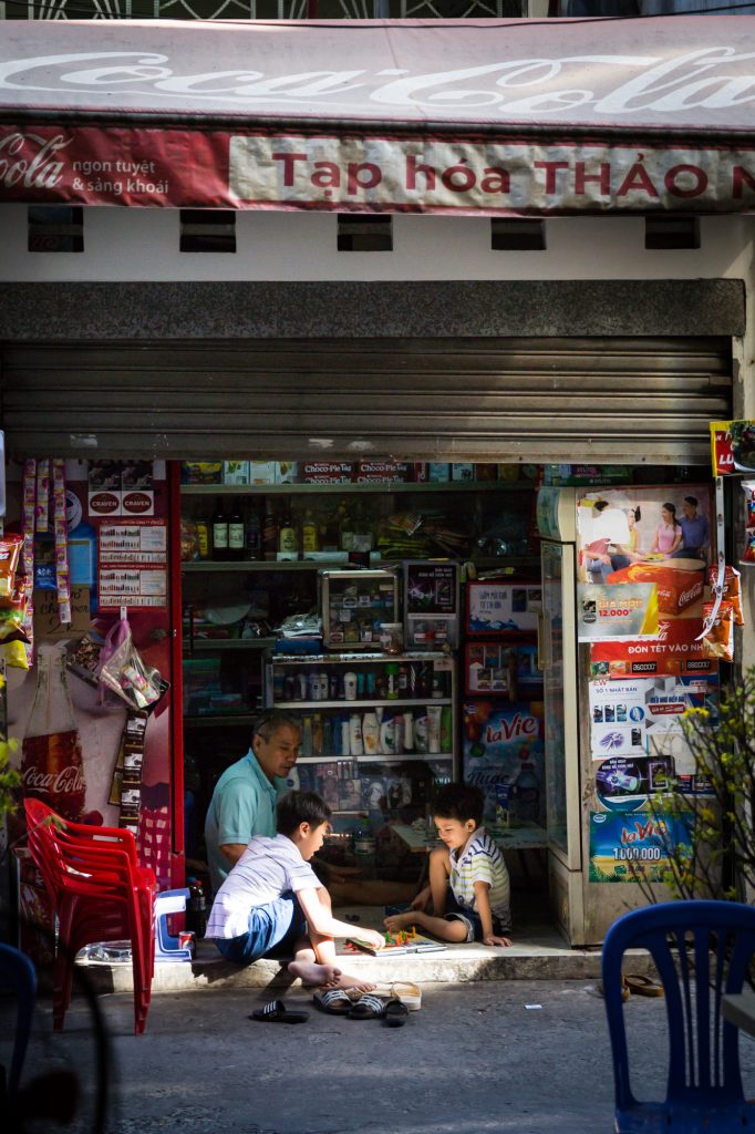 Grandfather and children playing a board game for article on Ho Chi Minh City street photos