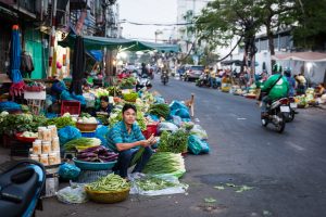 Man selling vegetables in the street for article on Ho Chi Minh City street photos