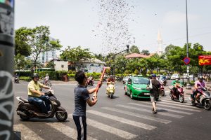 Man exploding a fire cracker in the street for article on Ho Chi Minh City street photos
