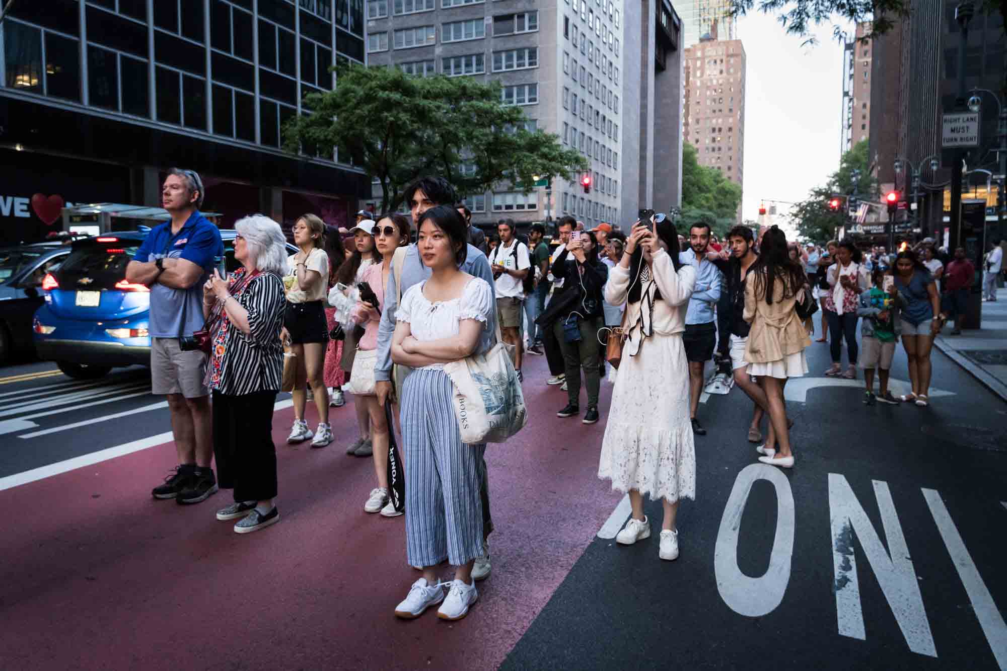 Tourists in a NYC street with cellphones in hand during Manhattanhenge