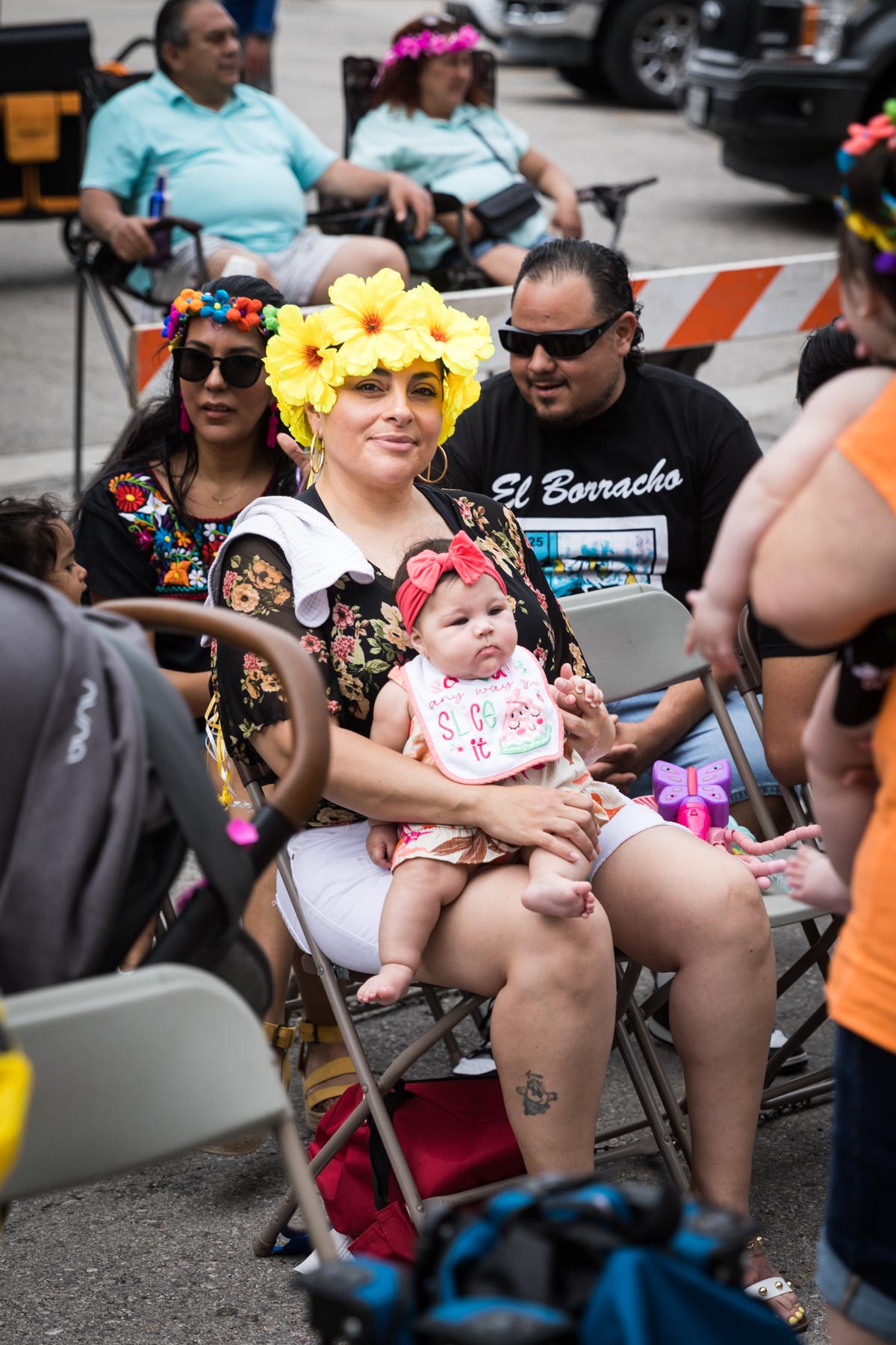 Woman sitting wearing yellow flower hat and holding baby for an article on the Fiesta photo tips