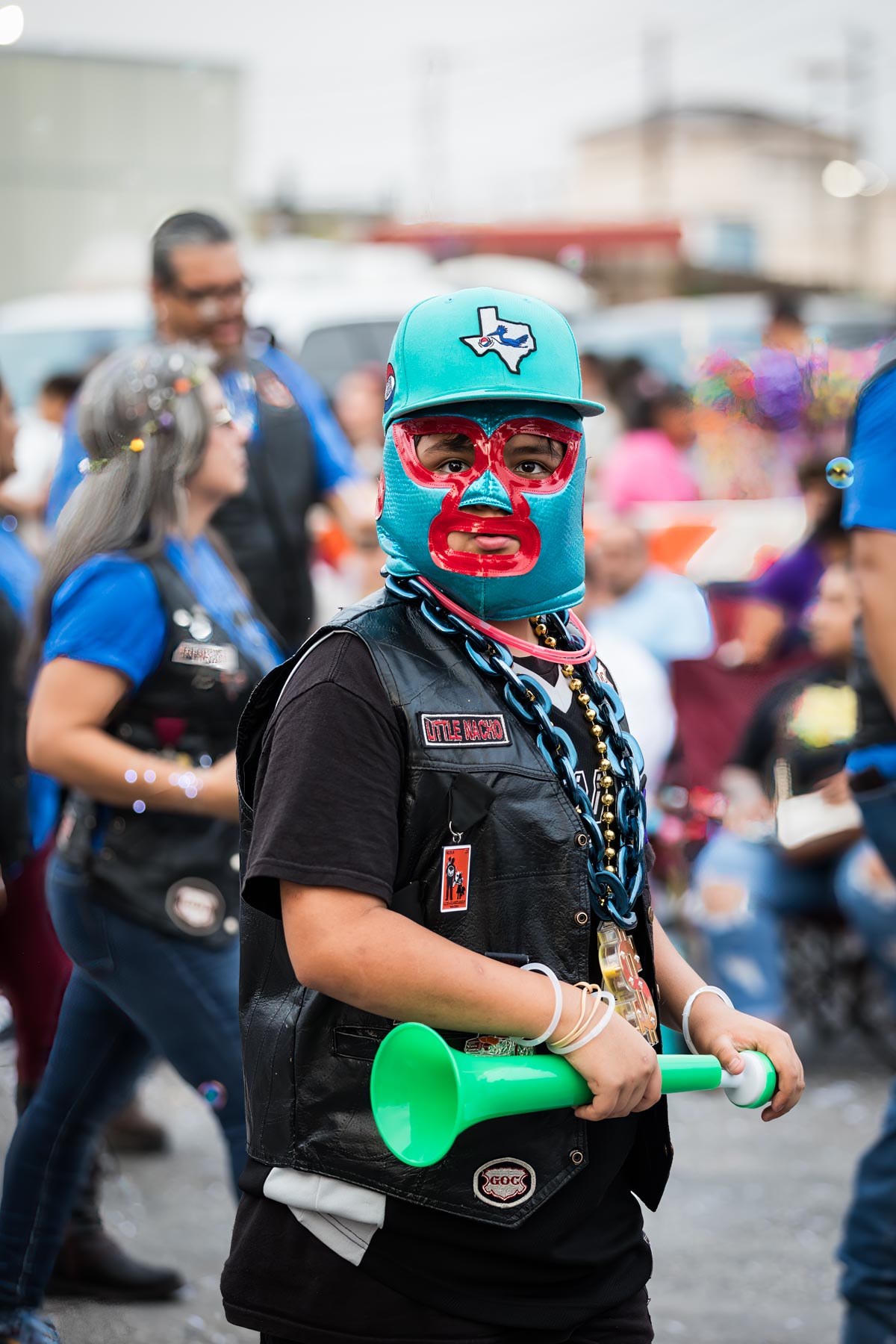 Man wearing mask and blue hat holding green horn for an article on the Fiesta photo tips