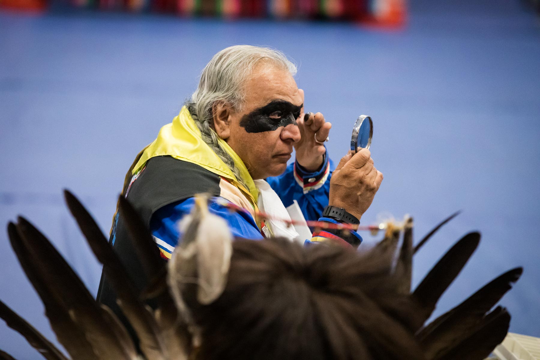 Man putting on Native American black eye makeup at pow wow for an article on the Fiesta photo tips