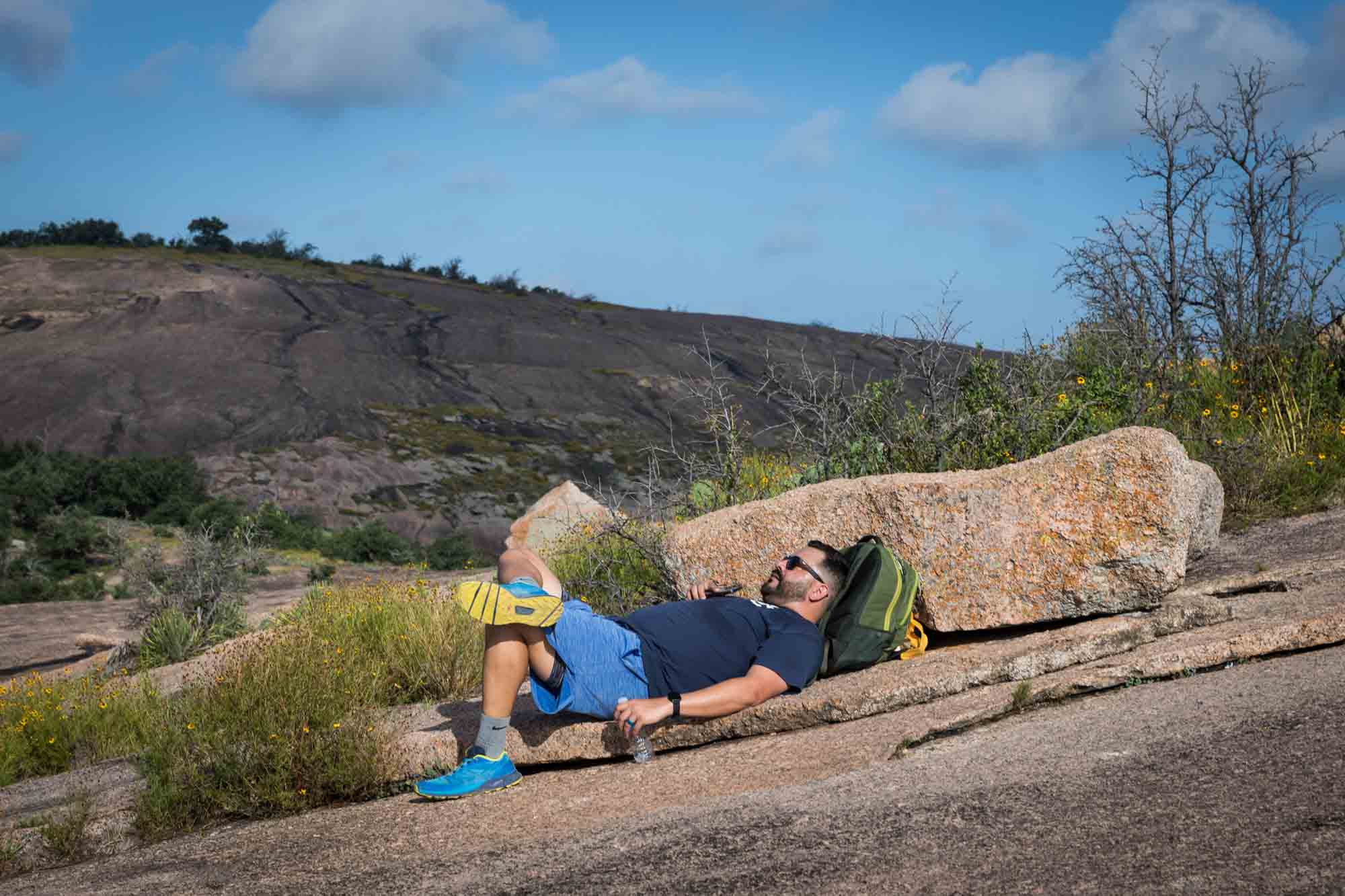 Man lying down on mountain on backpack for an article on Enchanted Rock hiking trips