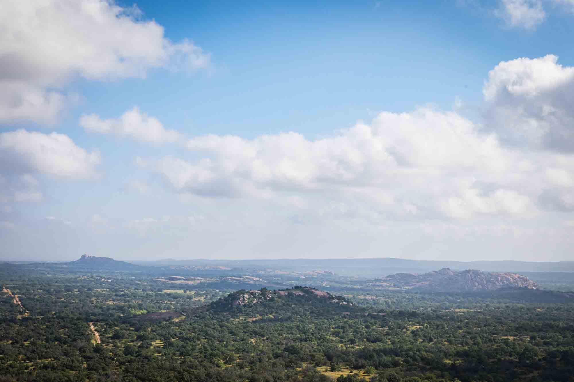 Three mountains surrounded by trees with clouds overhead for an article on Enchanted Rock hiking trips