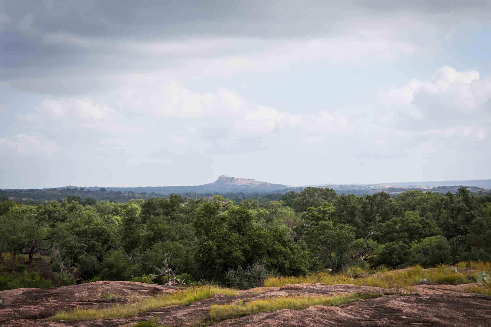 View of mountain in the distance with trees in foreground for an article on Enchanted Rock hiking trips