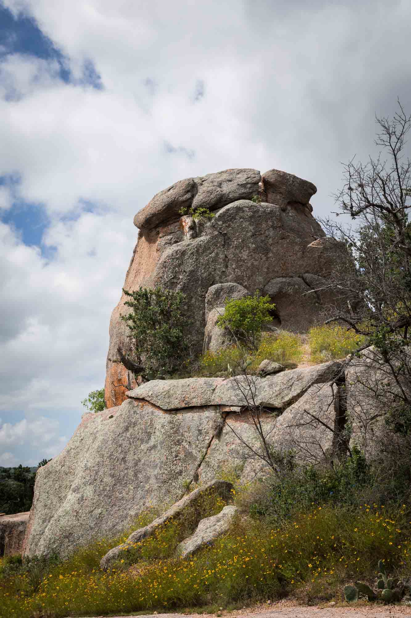 Large rock formation against clouds in the sky for an article on Enchanted Rock hiking trips