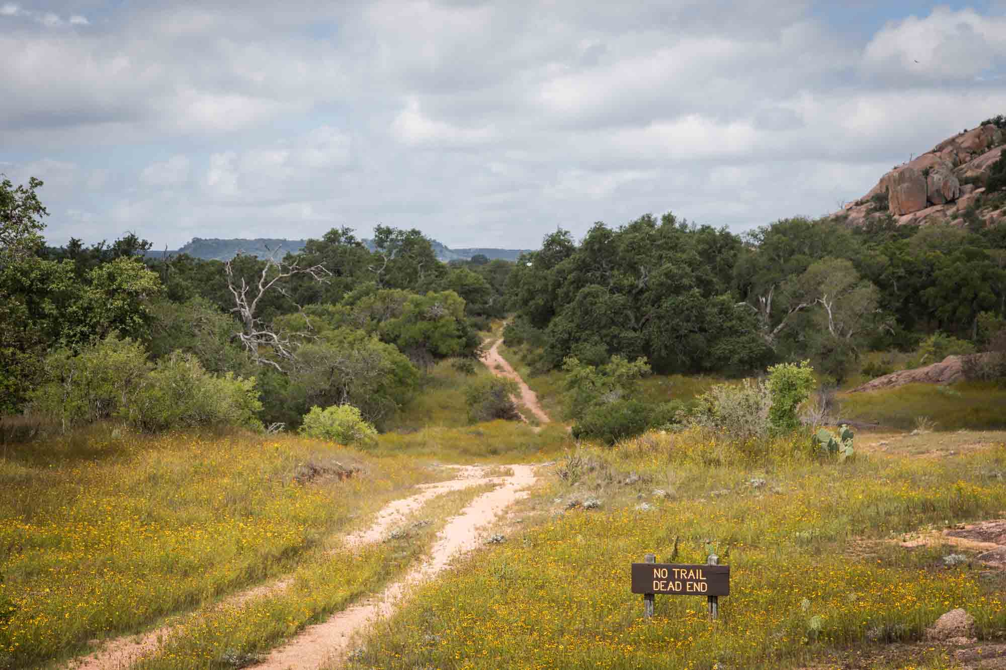 Pathway leading through trees with a sign that says No Trail Dead End for an article on Enchanted Rock hiking trips