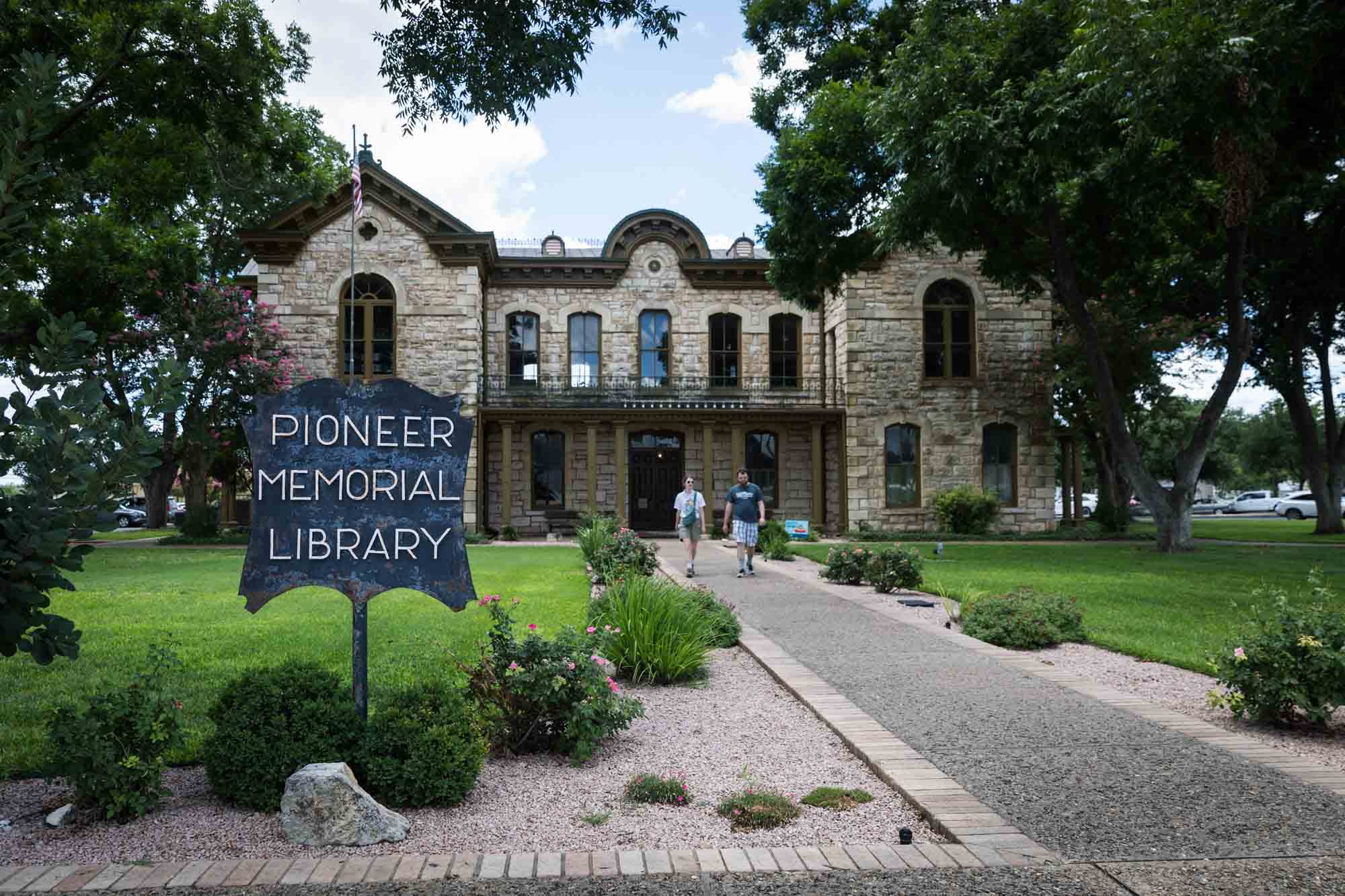 Two people walking down pathway from Pioneer Memorial Library in Fredericksburg