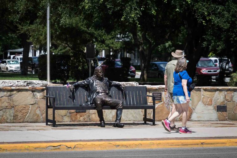 Couple walking past metal sculpture on a bench for an article entitled, ‘Visiting Boerne, Texas: Everything You Need to Know’