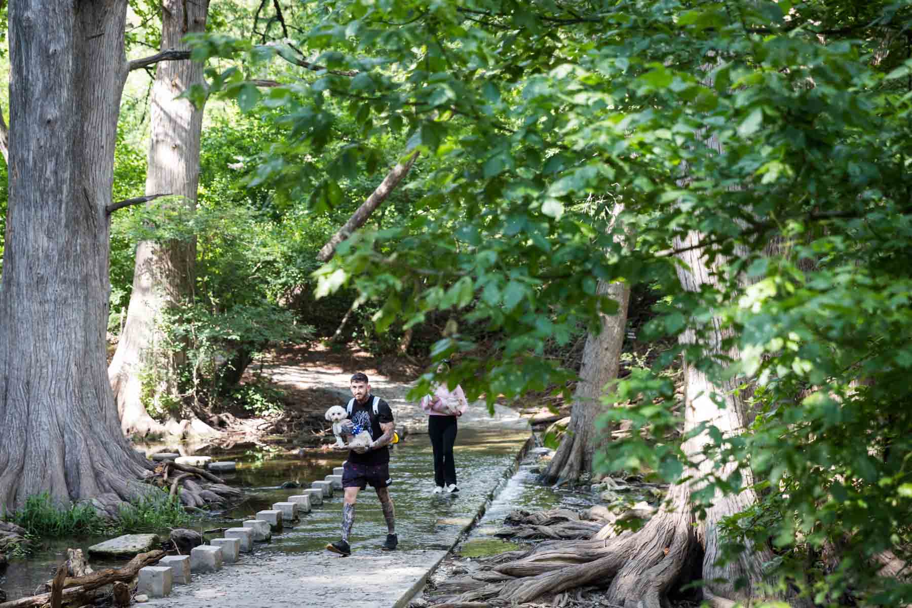 Couple carrying dogs through water in Cibolo Center for Conservation for an article entitled, ‘Visiting Boerne, Texas: Everything You Need to Know’