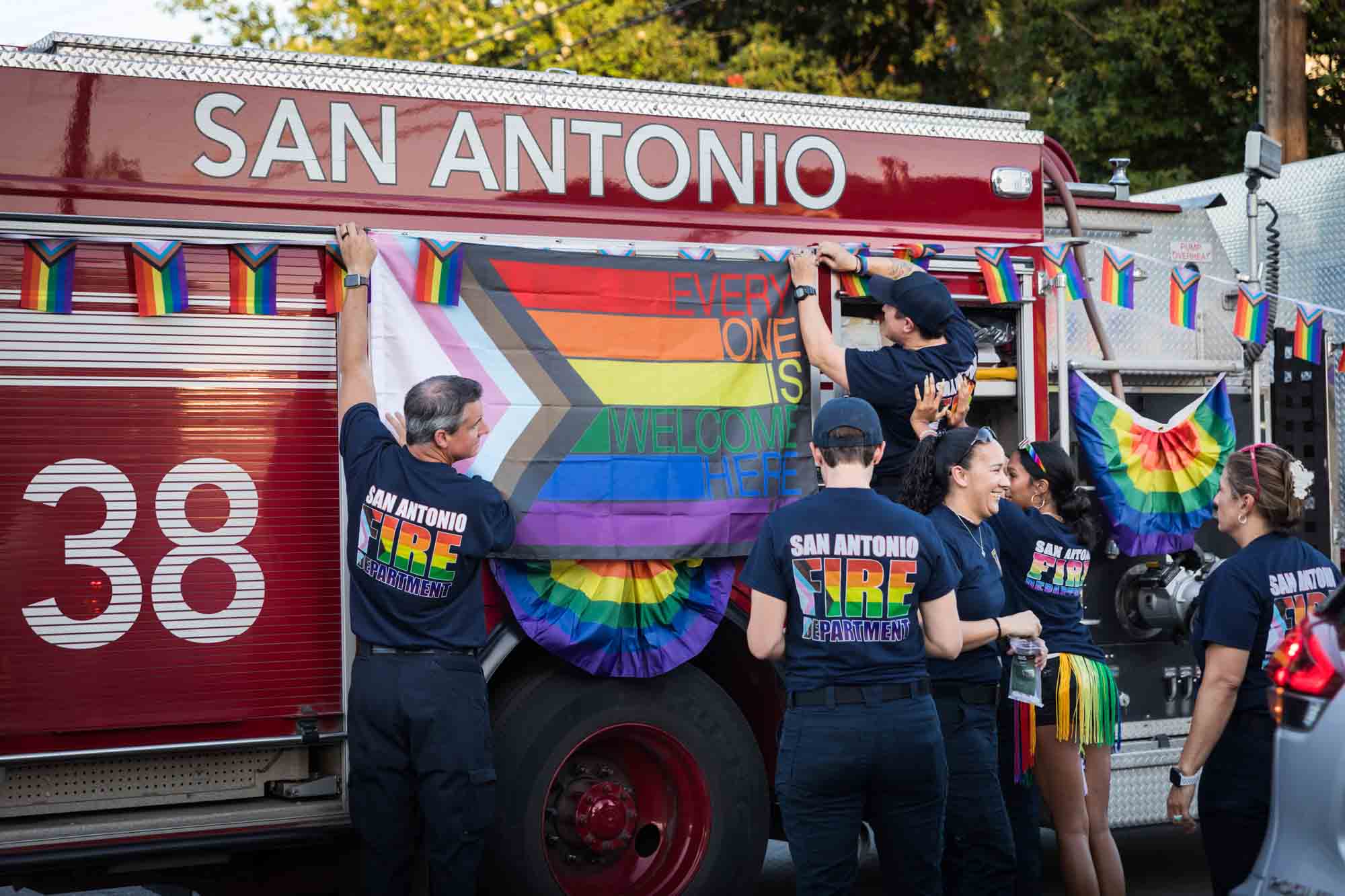 San Antonio gay pride parade photos of fire fighters decorating fire truck with rainbow flag