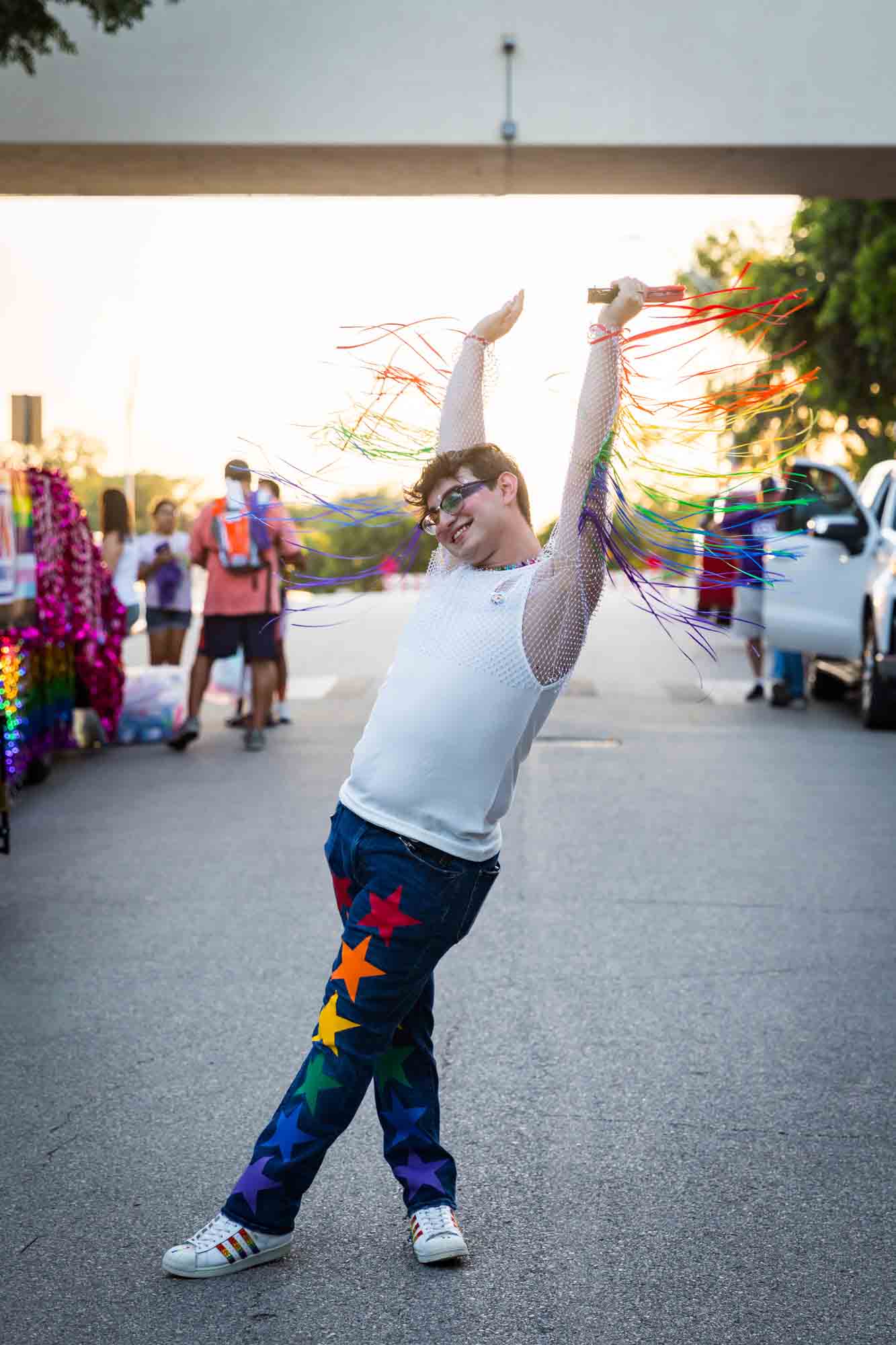 San Antonio gay pride parade photos of man wearing rainbow fringe on his arms dancing with arms above his head