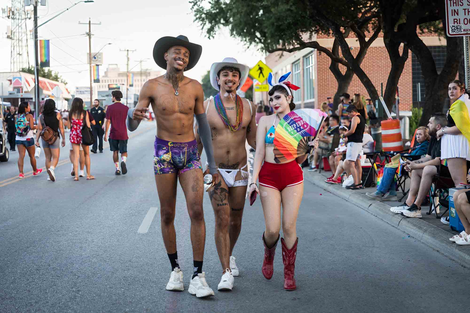 San Antonio gay pride parade photos of three nearly naked, colorfully dressed people walking in street