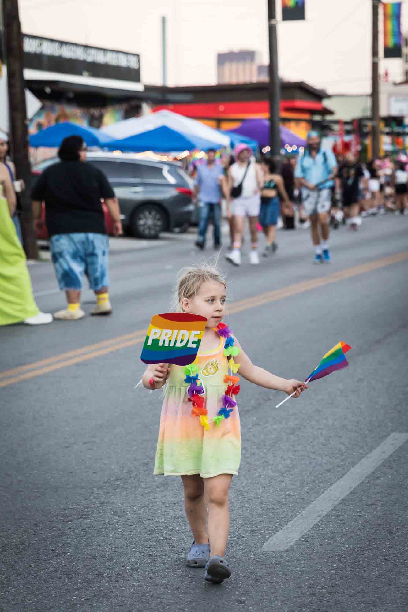 San Antonio gay pride parade photos of a little girl in the street holding two rainbow fans