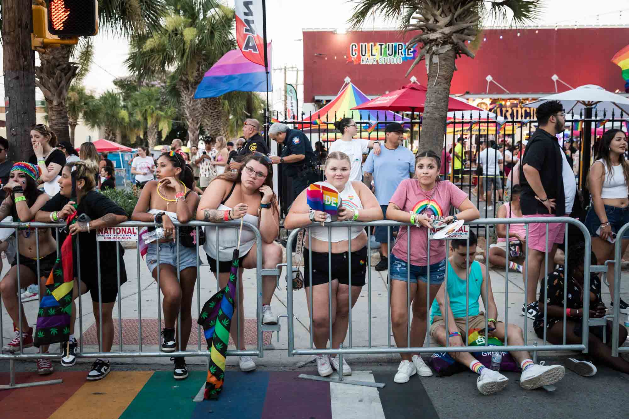 San Antonio gay pride parade photos of people leaning against metal railing waiting for parade to begin