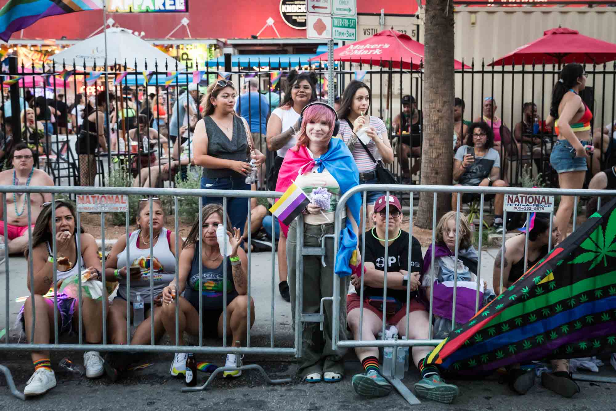 San Antonio gay pride parade photos of people leaning against metal railing waiting for parade to begin