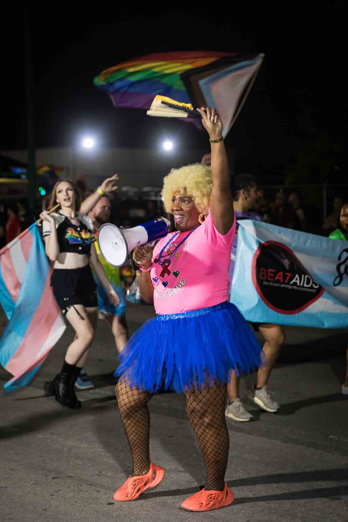 San Antonio gay pride parade photos of African American woman wearing pink shirt and blue shirt holding bullhorn in parade