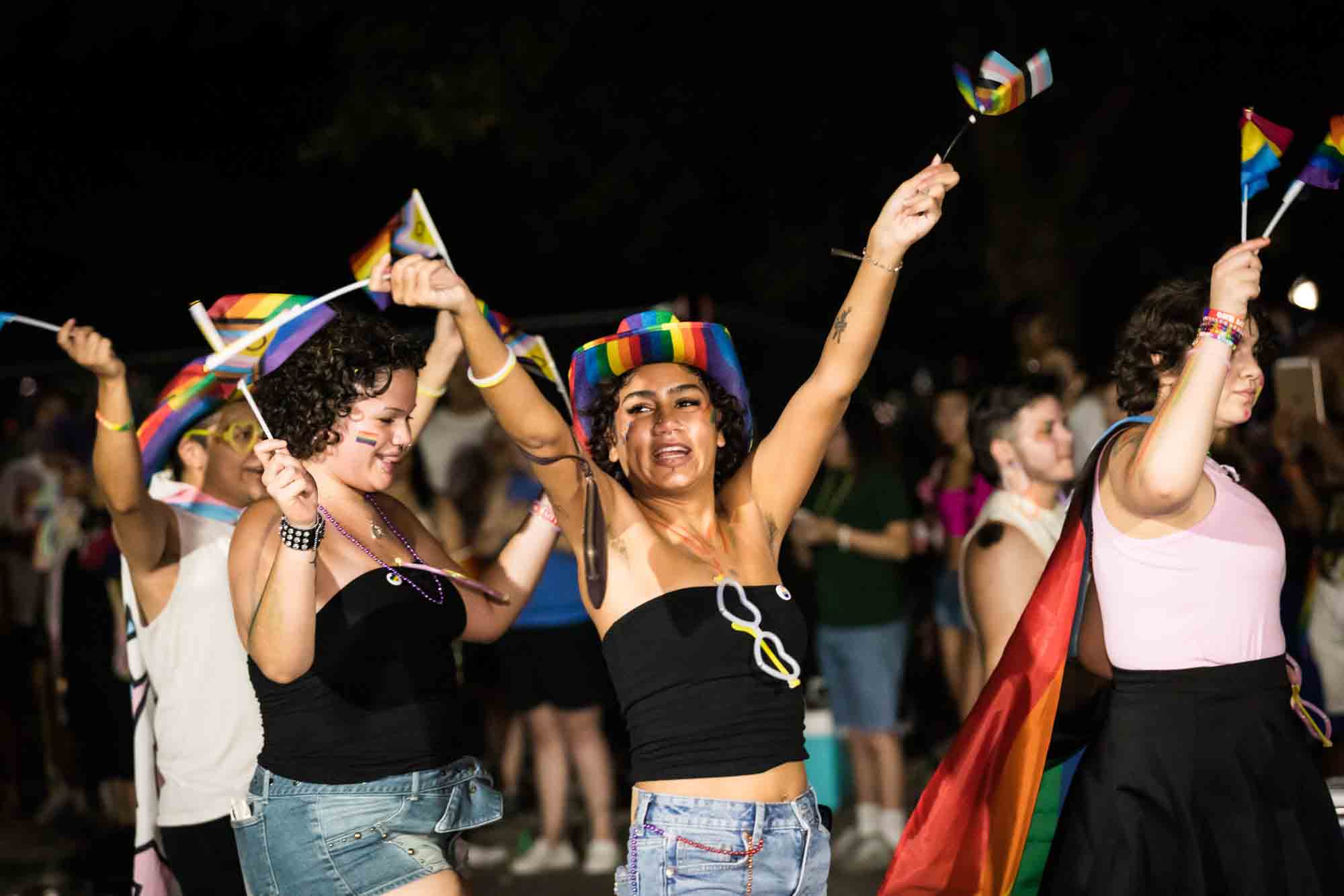 San Antonio gay pride parade photos of woman wearing black sleeveless shirt and arms outstretched in parade