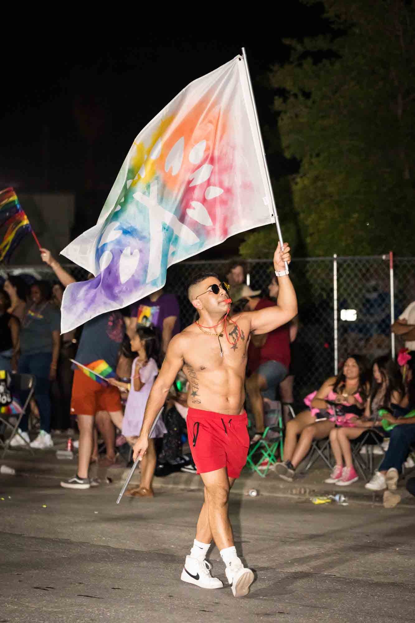 San Antonio gay pride parade photos of man wearing red shorts and waving large flag in parade