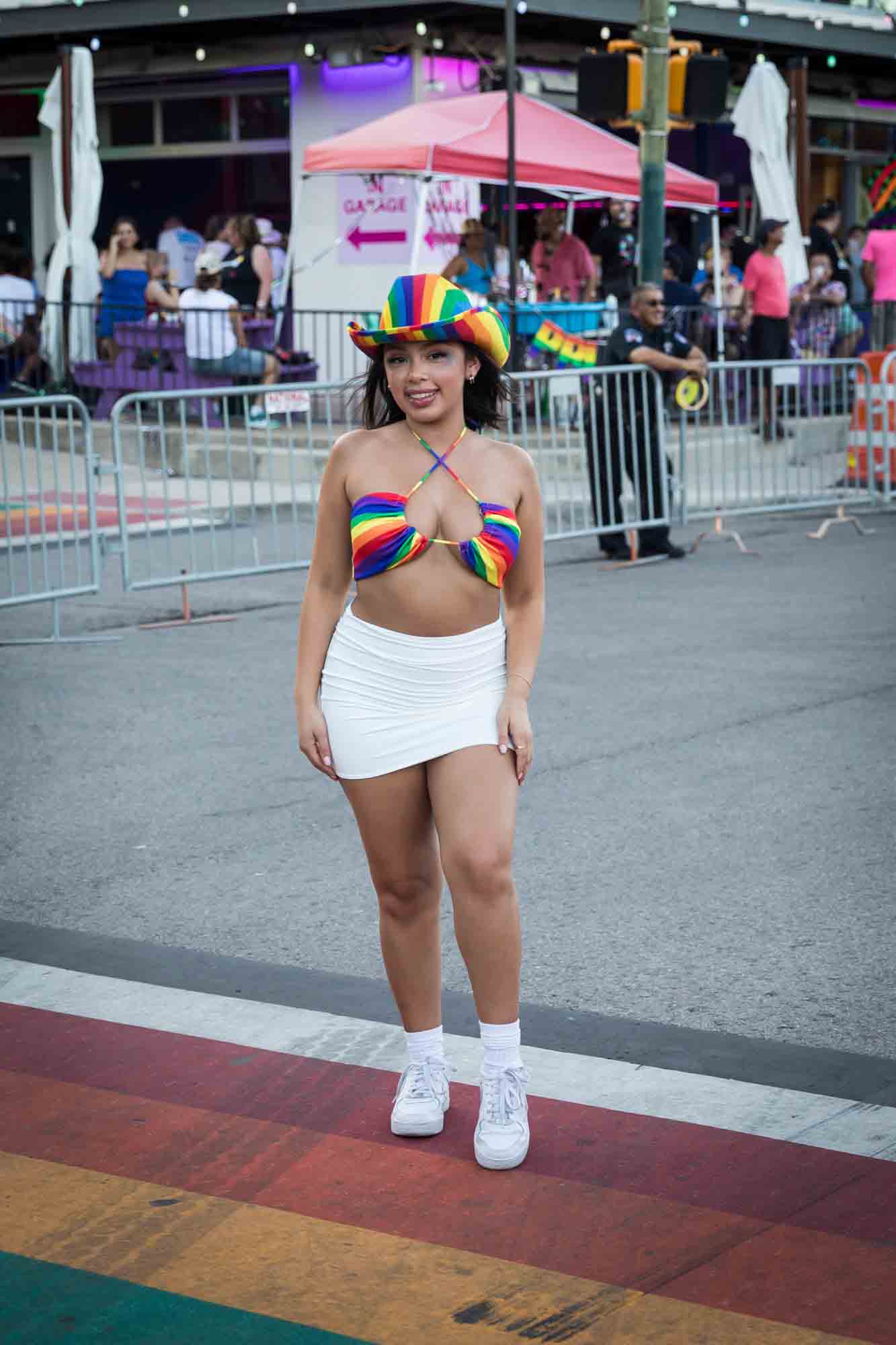 San Antonio gay pride parade photos of woman wearing rainbow bikini top and hat on rainbow road signage