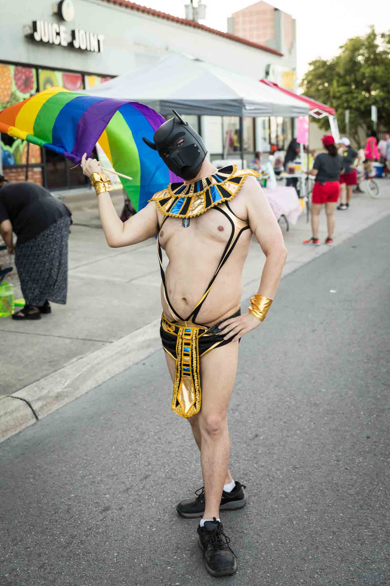 San Antonio gay pride parade photos of colorful character waving rainbow flag and wearing dog mask